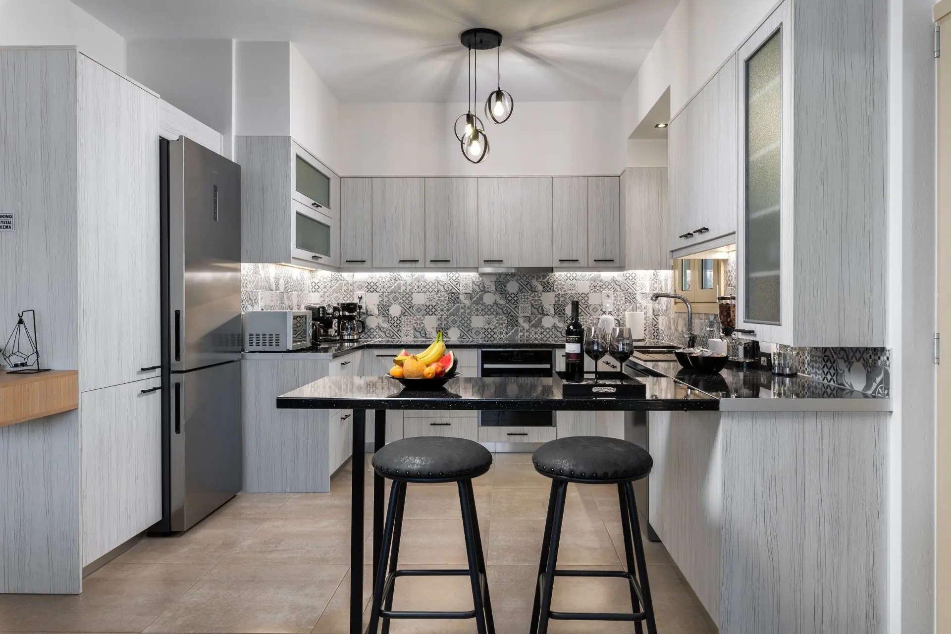 Modern kitchen with breakfast bar, stools, fruit bowl, and wine setup at Ria's Apartment in Agios Nikolaos.
