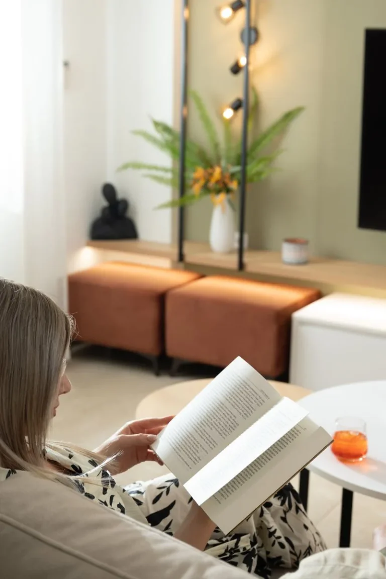 A guest relaxing on a comfortable sofa and reading a book in the modern living room at Ria's Apartment in Agios Nikolaos.