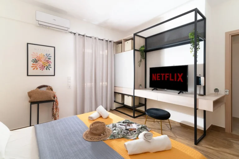 Interior view of the second bedroom at Ria's Apartment in Agios Nikolaos, showcasing a smart TV with Netflix, custom wardrobe, and fresh towels on the bed.