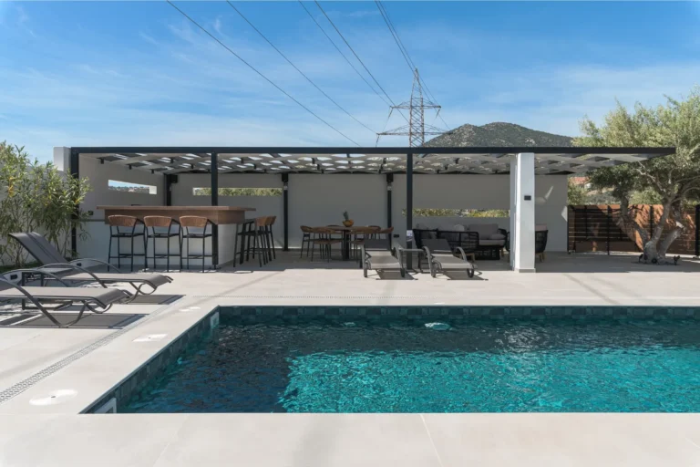 Luxury outdoor swimming pool with a bar, seating area, and mountain view at Ria's Apartment.