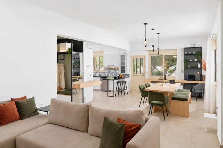 Bright open-plan living room, dining area, and kitchen with tile floors at Ria's Apartment in Agios Nikolaos.