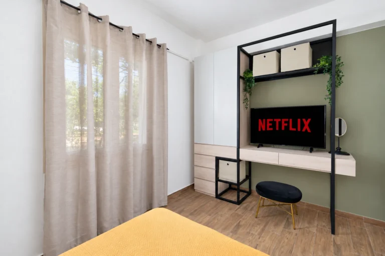 A modern custom wardrobe with a built-in vanity desk and a Smart TV showing Netflix in the third twin bedroom at Ria Oasis Residence in Agios Nikolaos.