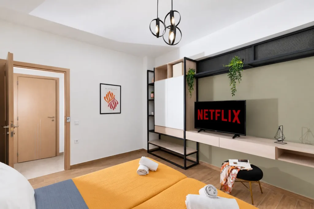 View of the master bedroom entryway, custom wardrobe unit, and smart TV with Netflix at Ria Oasis Residence in Agios Nikolaos.
