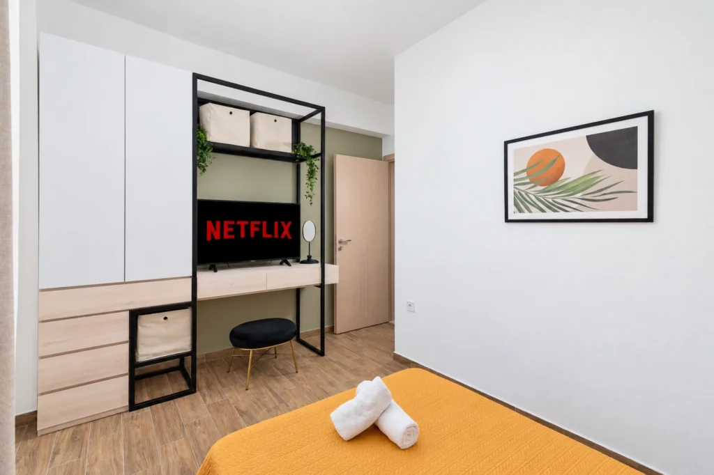 Interior view of the third bedroom at Ria Oasis Residence in Agios Nikolaos, with a smart TV on Netflix, custom wardrobe unit, and modern artwork.