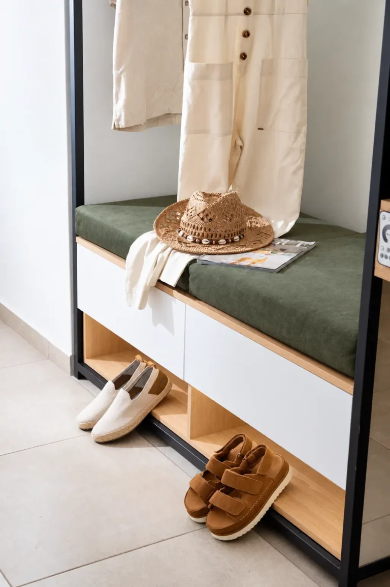 Close-up of a modern entryway unit with built-in shoe storage, ambient lighting, and a green velvet bench at Ria Oasis Residence in Agios Nikolaos.