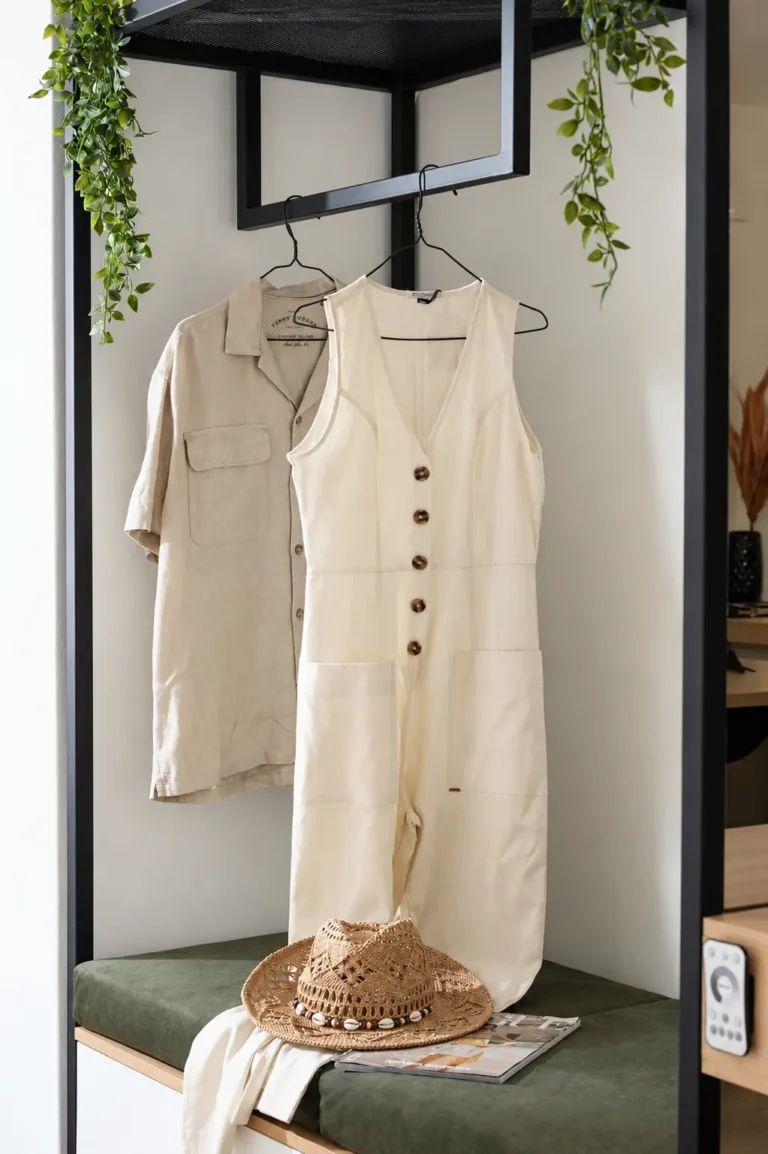 Close-up of a modern black metal clothes rack with linen garments above a green velvet bench at Ria Oasis Residence in Agios Nikolaos.