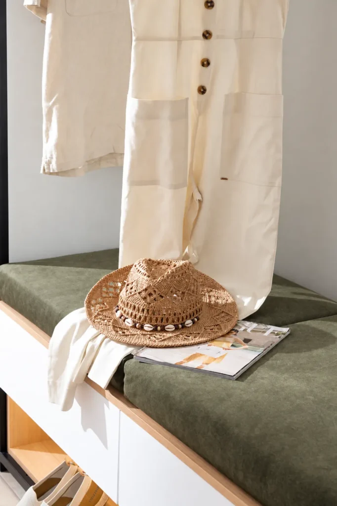 Close-up of a green velvet entrance bench with a straw hat, a Vogue magazine, and linen clothes at Ria Oasis Residence in Agios Nikolaos.