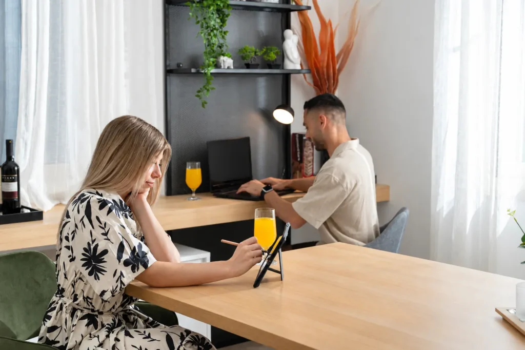 A couple working remotely using a laptop and tablet at the dedicated workspace in Ria Oasis Residence, Agios Nikolaos.