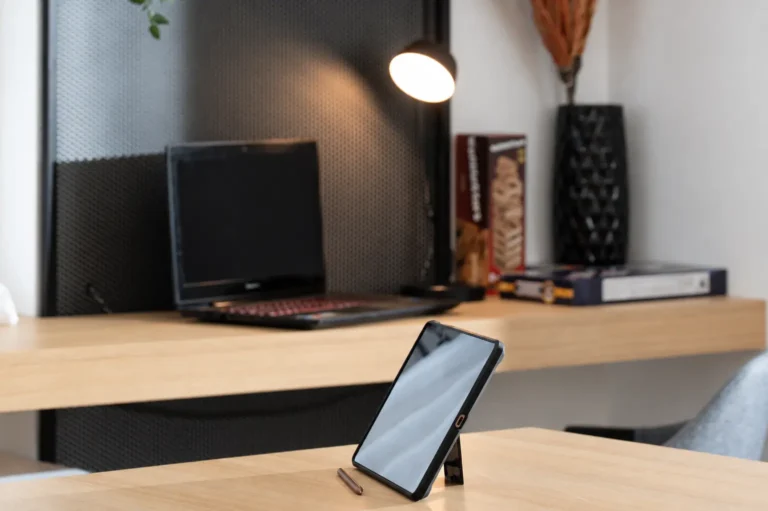 Close-up of a tablet with a stylus on a wooden table and a laptop at the modern workspace of Ria Oasis Residence in Agios Nikolaos.