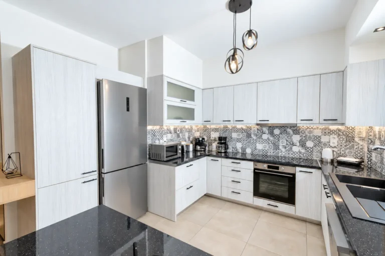 Ευρύχωρη κουζίνα του Ria Oasis Residence στον Άγιο Νικόλαο με ψυγείο inox, φούρνο, μικροκύματα, βραστήρα, τοστιέρα, καφετιέρες και διπλό νεροχύτη